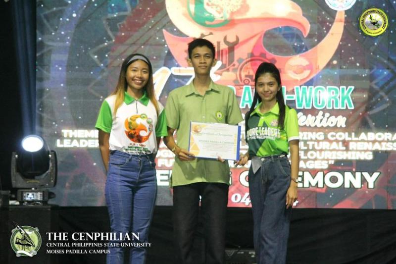A picture of John Berlin with 2 women with him showing his certification proving his Extemporaneous Speech victory during his college years.